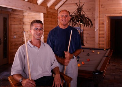 Mendon, MA (8208) owners in front of pool table, holding pool cues.