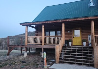 Small log cabin exterior view from in front of porch stairs.