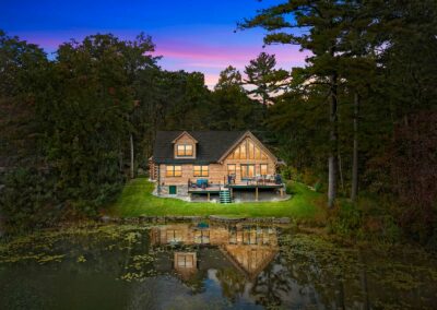 View of Spring Lake Log Home exterior from water at twilight.